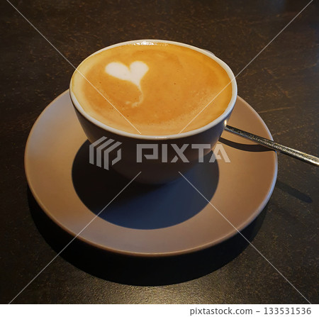 A cozy cup of cappuccino with a perfectly drawn heart on a delicate milk foam. Spectacular coffee art symbolizes love 133531536