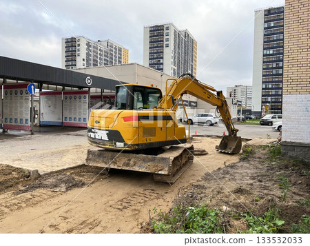 Excavator digs at construction site surrounded by residential buildings Excavator digs at construction site surrounded by residential buildings 133532033