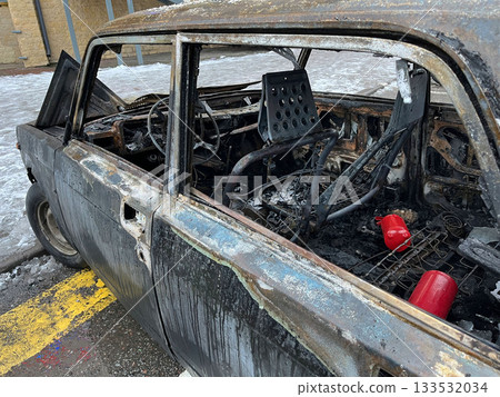 A charred car shows damage from a fire in a city setting A charred car shows damage from a fire in a city setting 133532034