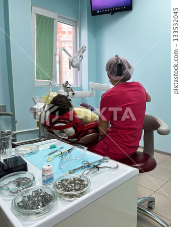 Dentist attends to patient in dental chair in a modern clinic 133532045