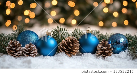 Blue baubles and pine cones with snow on evergreen branches 133532215