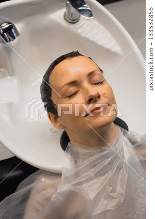 Woman washing hair in beauty salon. Beauty transformation. Hair dye concept. Hair colouring in beauty salon. Hairstyle concept. Beauty salon service. Hair stylist washing client's head. Woman washing hair in beauty salon. Beauty transformation. Hair dye concept. Hair colouring in beauty salon. Hairstyle concept. Beauty salon service. Hair stylist washing client's head. 133532856