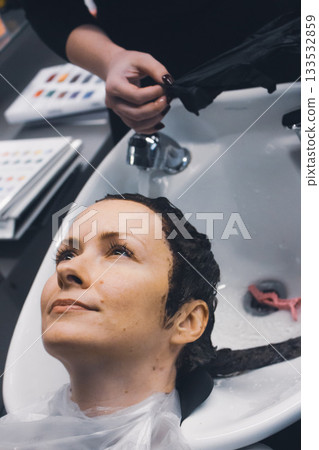 Woman washing hair in beauty salon. Beauty transformation. Hair dye concept. Hair colouring in beauty salon. Hairstyle concept. Beauty salon service. Hair stylist washing client's head. Woman washing hair in beauty salon. Beauty transformation. Hair dye concept. Hair colouring in beauty salon. Hairstyle concept. Beauty salon service. Hair stylist washing client's head. 133532859