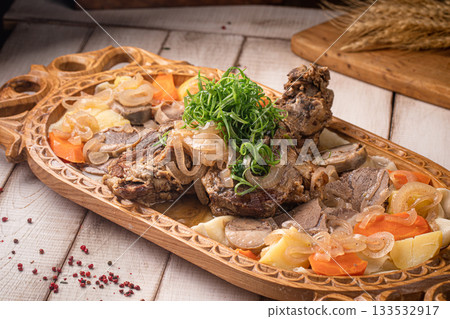 Festive beshbarmak served on traditional wooden platter 133532917