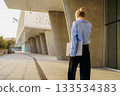 A stylish business woman stands confidently outside of a modern architectural building 133534383
