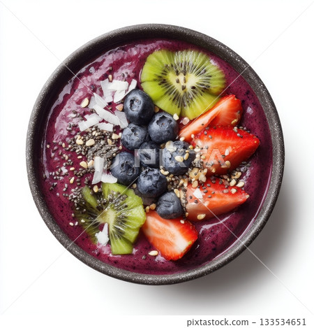 A dark bowl filled with vibrant purple smoothie topped with fresh blueberries sliced strawberries kiwi slices coconut 133534651