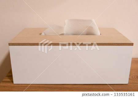 Minimalistic wooden tissue box with a white paper tissue sticking out. Neutral home interior 133535161