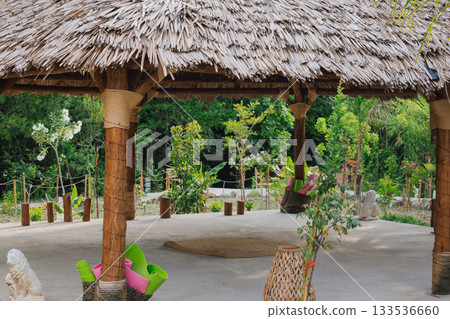 Gazebo with a thatched roof in the open air in a tropical garden for yoga. Veranda or terrace in Asian style for sports 133536660