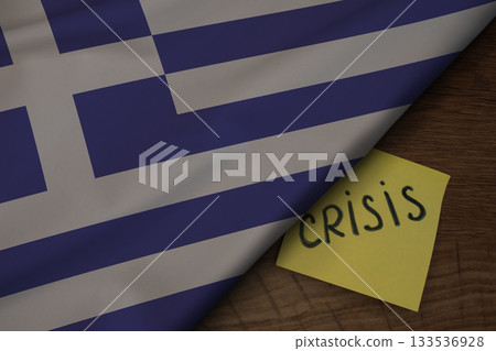 Fabric of the Greece flag on wooden surface and the word Crisis, concept of tense crisis situation in the country Fabric of the Greece flag on wooden surface and the word Crisis, concept of tense crisis situation in the country 133536928