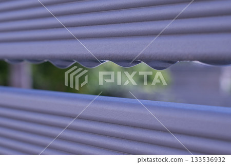 Water droplets trickling down a metal fence after rain 133536932