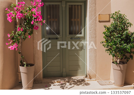 Flowers in pots near a beautiful green door, Mediterranean coziness of the old town of Rethymno Flowers in pots near a beautiful green door, Mediterranean coziness of the old town of Rethymno 133537097