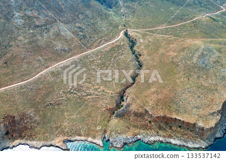 Scenic dirt road to Balos Bay on Crete with towering cliffs and turquoise sea 133537142
