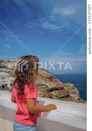 View of the Santorini seascape distant islands, young figure looking at the horizon 133537307
