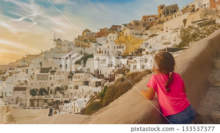 Child standing in a picturesque setting with famous whitewashed walls blue dome of island Santorini 133537377