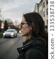 Thoughtful woman in glasses contemplating life on a city street during twilight 133538738
