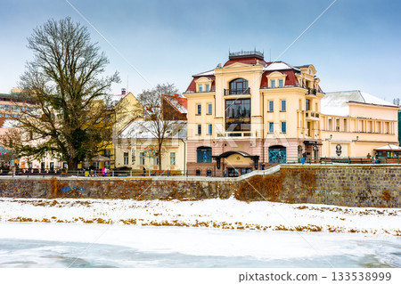 uzhhorod, ukraine - 09 jan 2017: christmas time in the old town in winter. snow covered embankment of ice frozen river uzh. cold weather. timeless photo of transcarpathia capital on holiday season 133538999