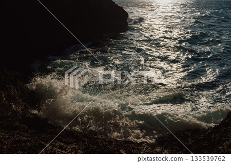 View from a cave to the sea on sunny day in summer. Mediterranean beauty landscape. Waves crashing on a rocky beach View from a cave to the sea on sunny day in summer. Mediterranean beauty landscape. Waves crashing on a rocky beach 133539762