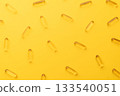 Top view of oil softgel capsules lie in rows diagonal on yellow background. Nutritional supplement contains fish oil, omega 3, omega 6, omega 9, vitamin e, vitamin d and vitamin a. 133540051