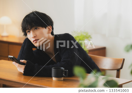 Young man looking at a smartphone in the room Young man looking at a smartphone in the room 133541003