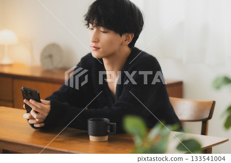 Young man looking at a smartphone in the room Young man looking at a smartphone in the room 133541004