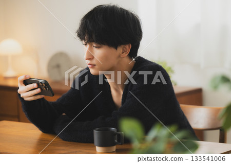 年輕人看著房間裡的智能手機 133541006
