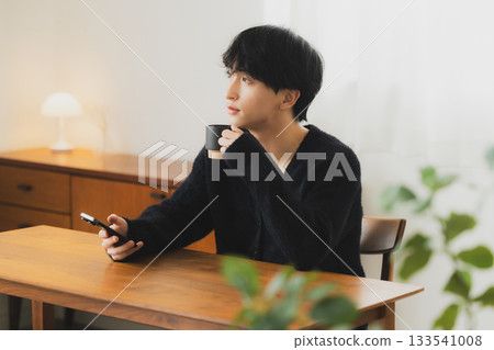 Young man looking at a smartphone in the room 133541008