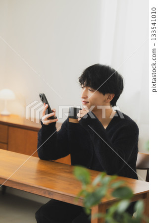 年輕人看著房間裡的智能手機 133541010