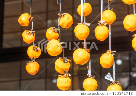 Peeled orange dried persimmons hanging from the eaves 133541718