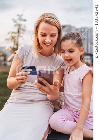 Mother and Daughter Shopping Online Using a Smartphone and Credit Card 133542943