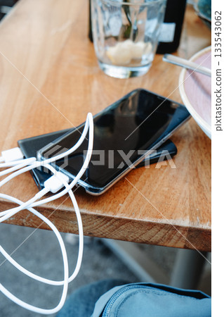 a smartphone charging beside used dishes 133543062