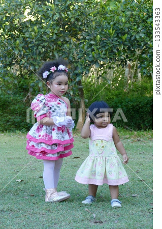 Happy cute Asian little girls playing in the garden, Thailand. 133543363