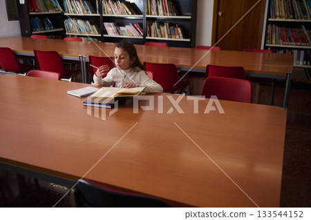 Young Student Reading and Studying Alone in a Library During Quiet Study Time 133544152