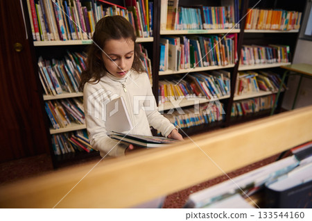 Young Girl in Library Chooses Books, Learning and Reading in School Library 133544160