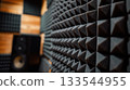 Close-up of a soundproof foam wall, showcasing the geometric patterns of acoustic panels in a recording studio environment. 133544955