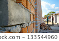 Brick wall being constructed with fresh cement, highlighting the craft of masonry and the process of building. 133544960