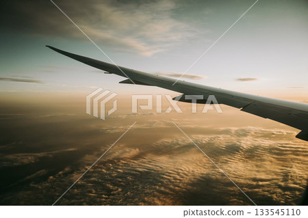 Airplane wing above the clouds during golden hour flight 133545110
