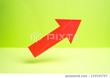 A red arrow pointing upward hovers on a green background. Concept of growth and expansion. Economic rise and business performance. Success metrics. Financial forecasting. 133545747