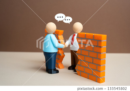 Businessmen shake hands through a gap in the wall. To break through the wall of misunderstanding. To reach a compromise. Cooperation, conflict management and cross-border partnership. Businessmen shake hands through a gap in the wall. To break through the wall of misunderstanding. To reach a compromise. Cooperation, conflict management and cross-border partnership. 133545802