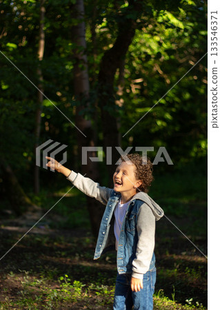Inquisitive boy exploring something in public park. Park setting and boy wonder are perfect for themes of adventure and exploration. High quality photo. 133546371