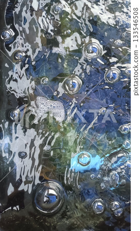 Sparkling water bubbles on reflective surface with blue and green tones, dynamic abstract texture and shimmering highlights 133546508