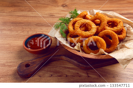Deep fried onion rings, appetizer, with tomato sauce, on a wooden table, no people, favorite dish, 133547711