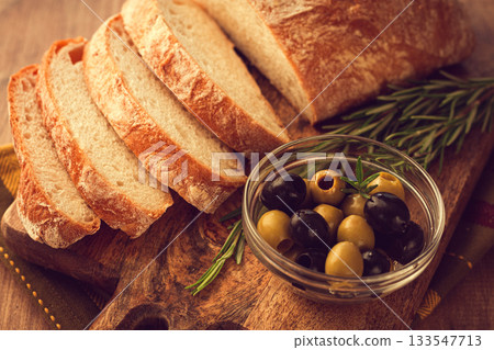 sliced ciabatta , on a chopping board, with rosemary and olives, Italian bread, close-up, Italian cuisine, breakfast, no people, sliced ciabatta , on a chopping board, with rosemary and olives, Italian bread, close-up, Italian cuisine, breakfast, no people, 133547713
