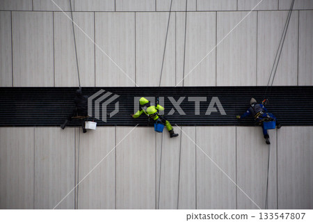 Industrial climbers clean ventilation pipe outlet at high altitude. Maintenance of the ventilation system. Complex work with increased risk Industrial climbers clean ventilation pipe outlet at high altitude. Maintenance of the ventilation system. Complex work with increased risk 133547807