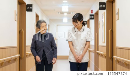 A female caregiver assisting an elderly person in walking 133547874