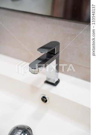 Close-up view of modern chrome bathroom faucet showcasing reflective metal surface and minimalist style 133548137
