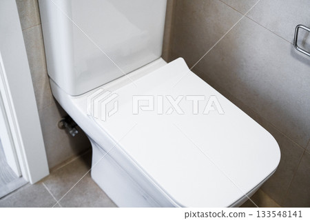 Side view of modern white toilet with clean ceramic surfaces in bright minimalist bathroom 133548141