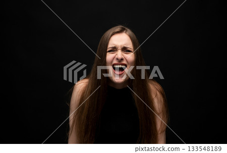 Young woman bursts into expressive laughter in a studio portrait 133548189
