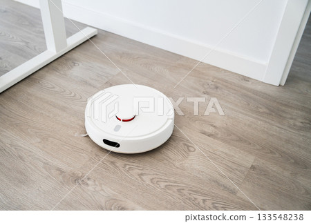 Smart robot vacuum navigating wide wooden floor area while cleaning modern interior living space efficiently 133548238