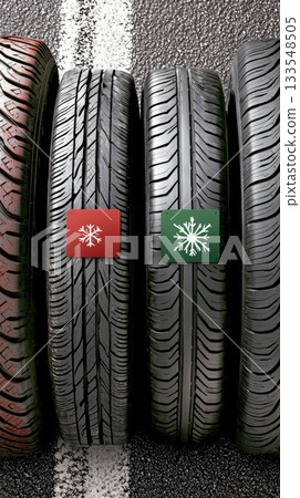 A snowy road surrounded by trees features a stack of tires and a warning sign, emphasizing the importance of safe winter driving 133548505