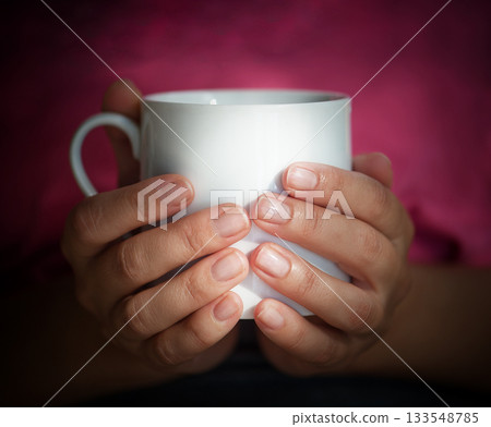 Female hands hold a white cup 133548785